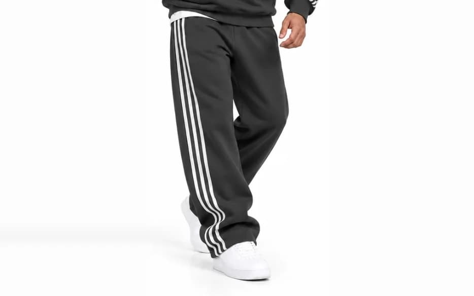 Model wearing charcoal grey wide-leg sweatpants with three white side stripes, front view, no logo